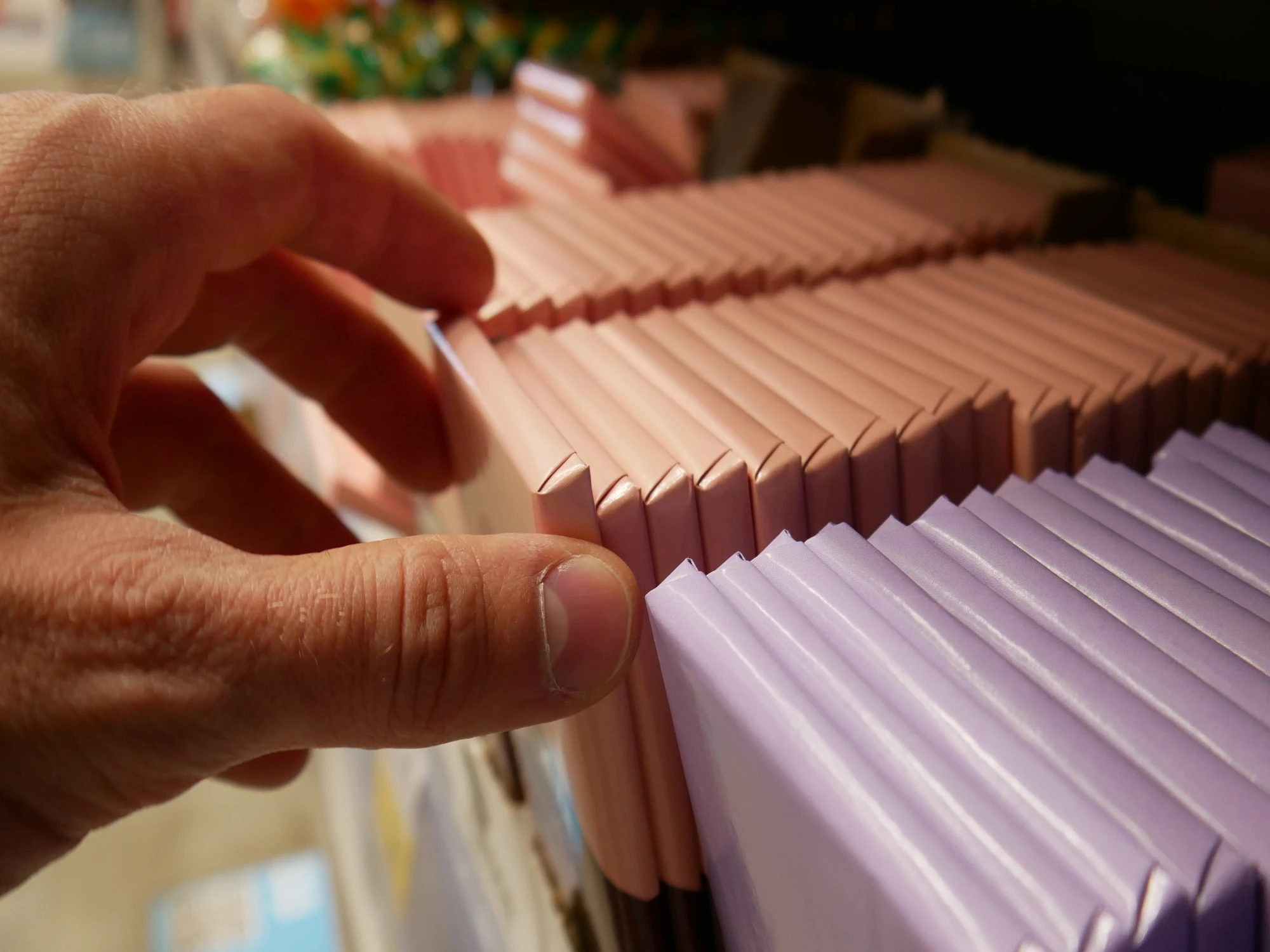 Close up of person selecting chocolate bar from a shelf in a store.