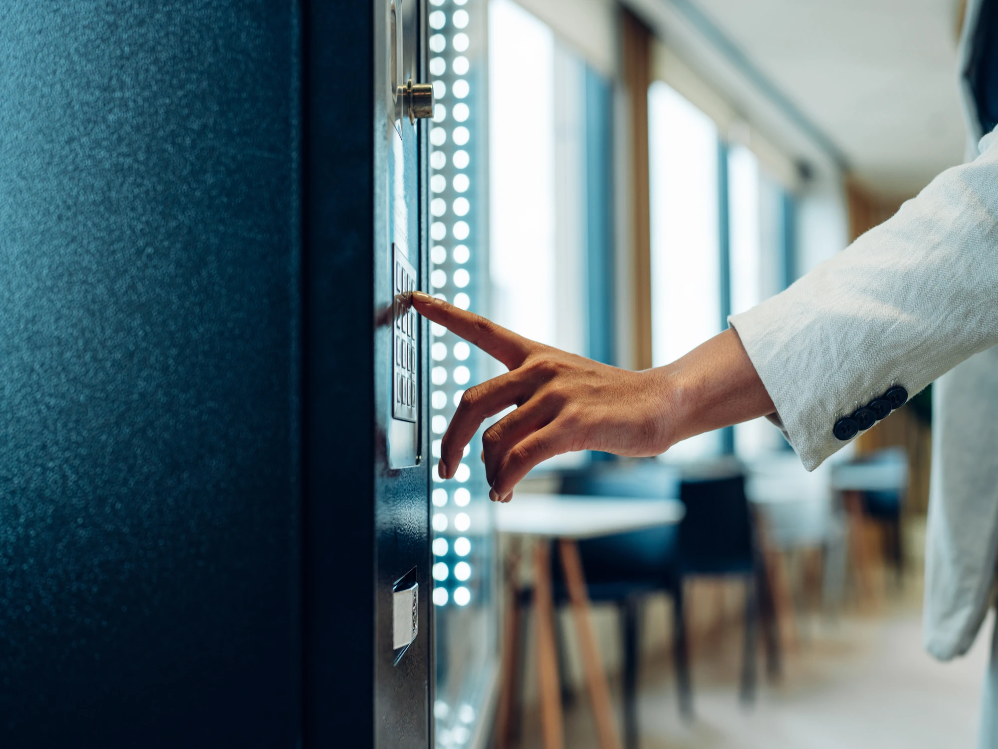 Person pressing button on vending machine in office building.